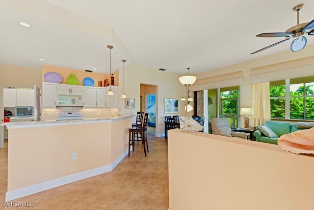 kitchen featuring white appliances, backsplash, white cabinets, decorative light fixtures, and a breakfast bar area