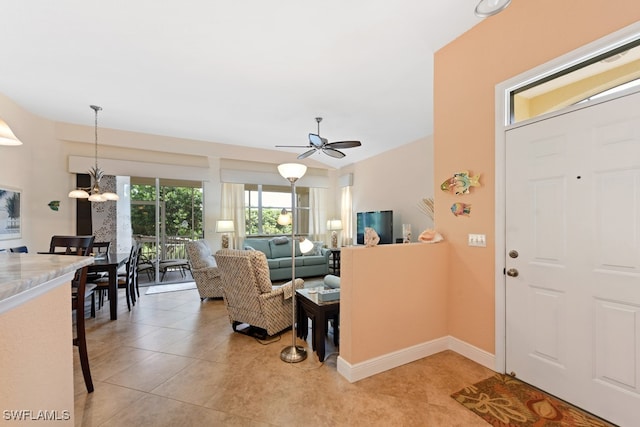 tiled entrance foyer with ceiling fan with notable chandelier