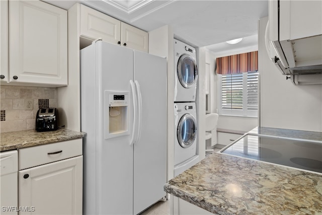 kitchen with light stone counters, tasteful backsplash, white appliances, white cabinets, and stacked washer and dryer