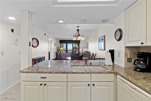 kitchen with light stone counters, dishwasher, kitchen peninsula, a notable chandelier, and sink