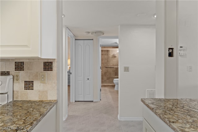 kitchen with light tile patterned flooring, white cabinetry, backsplash, and light stone counters