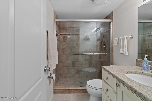 bathroom featuring vanity, a shower with shower door, tile patterned floors, and toilet