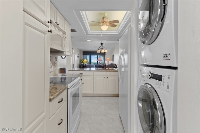 laundry area featuring light tile patterned floors, stacked washer and dryer, and ceiling fan with notable chandelier