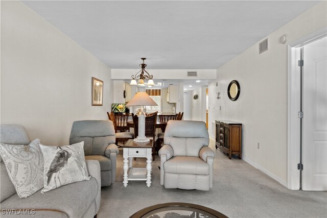 carpeted living room featuring an inviting chandelier