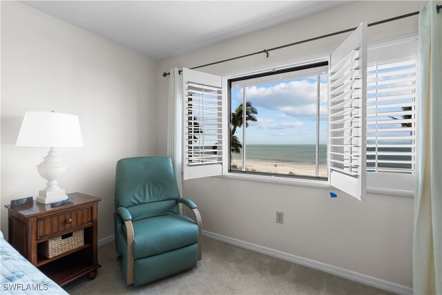 living area with a view of the beach, carpet flooring, and a water view