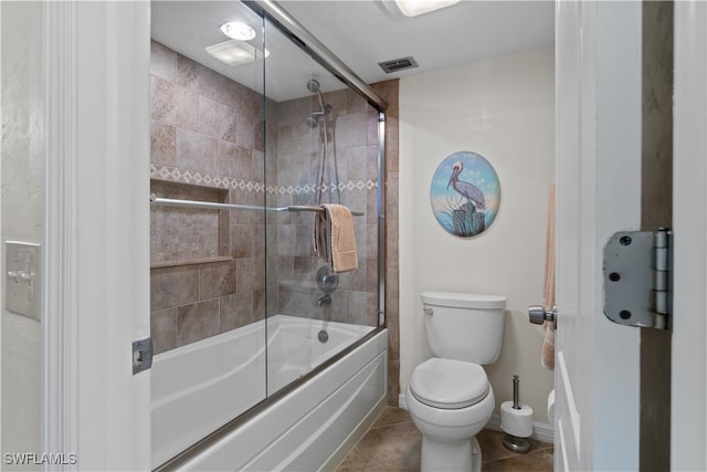 bathroom featuring toilet, bath / shower combo with glass door, and tile patterned floors