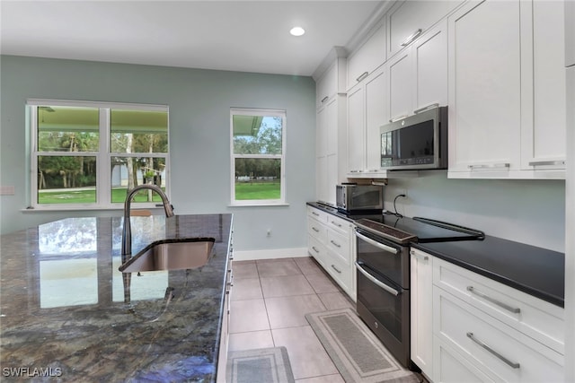 kitchen featuring white cabinets, sink, stainless steel appliances, and dark stone counters