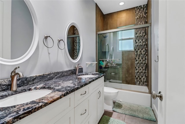 full bathroom with tile patterned flooring, vanity, toilet, and bath / shower combo with glass door