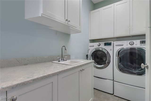 laundry area featuring washing machine and clothes dryer, sink, light tile patterned floors, and cabinets