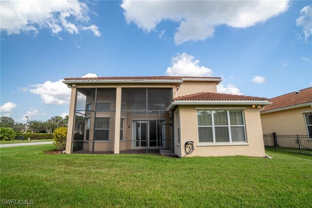 rear view of house featuring a yard and a sunroom