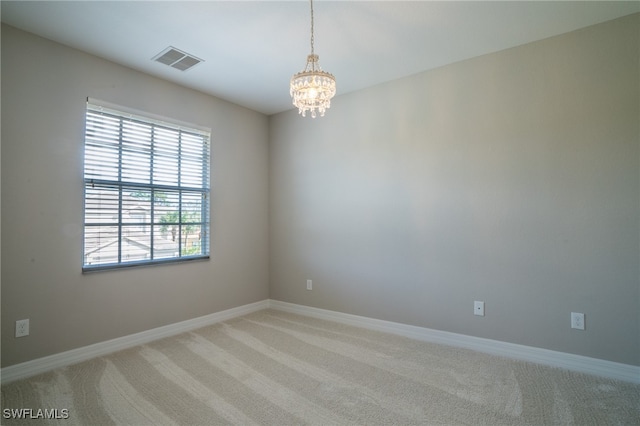 carpeted empty room featuring a notable chandelier