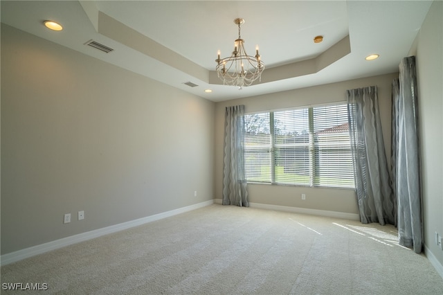 carpeted empty room featuring a raised ceiling and a notable chandelier