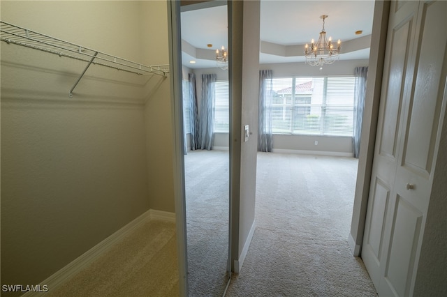 spacious closet featuring a notable chandelier and light colored carpet