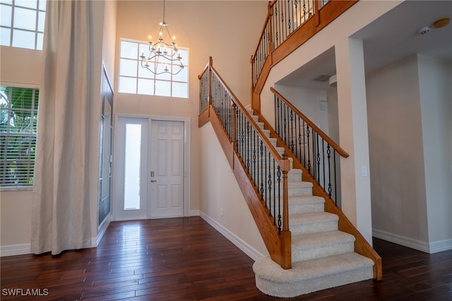 entrance foyer with a healthy amount of sunlight, a chandelier, dark hardwood / wood-style floors, and a high ceiling