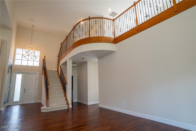 entrance foyer featuring a high ceiling, dark wood-type flooring, and an inviting chandelier