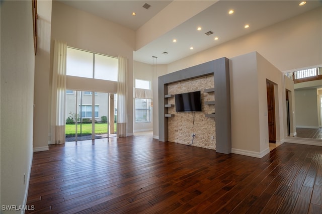 unfurnished living room with a high ceiling and dark hardwood / wood-style flooring