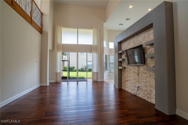 unfurnished living room with a towering ceiling and dark hardwood / wood-style flooring