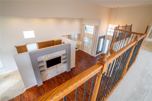 stairs with high vaulted ceiling, a chandelier, and wood-type flooring