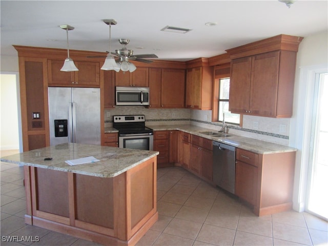 kitchen featuring light stone counters, light tile patterned floors, appliances with stainless steel finishes, a kitchen island, and sink