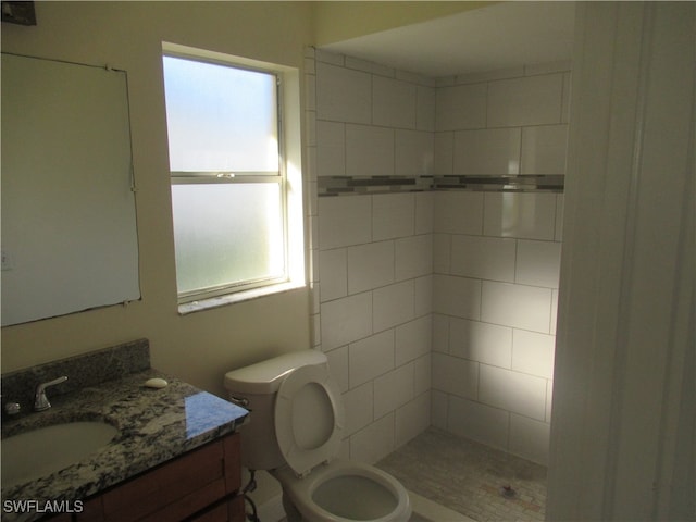 bathroom featuring toilet, vanity, and tiled shower