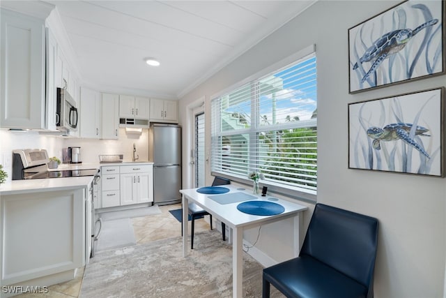 kitchen featuring tasteful backsplash, exhaust hood, appliances with stainless steel finishes, white cabinetry, and ornamental molding