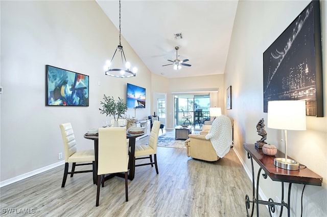 dining room featuring high vaulted ceiling, hardwood / wood-style floors, and ceiling fan with notable chandelier