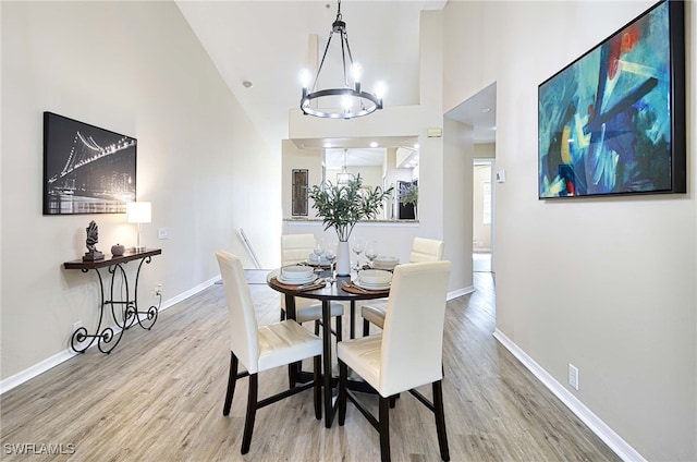 dining area featuring wood-type flooring, a chandelier, and a high ceiling