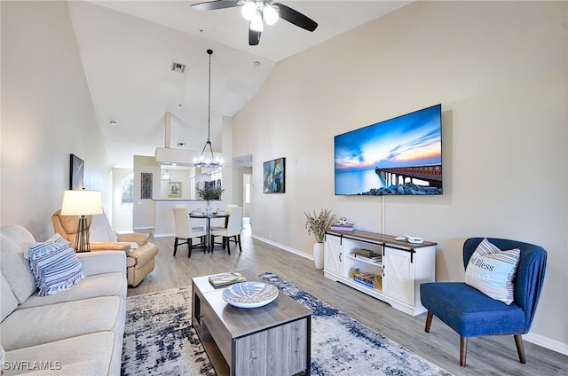 living room featuring hardwood / wood-style floors, ceiling fan with notable chandelier, and high vaulted ceiling