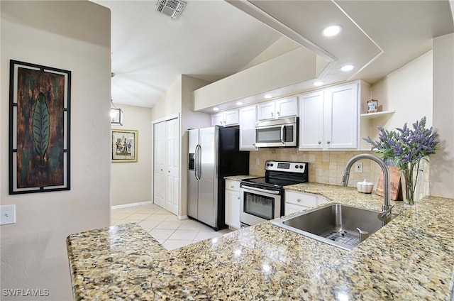 kitchen featuring stainless steel appliances, vaulted ceiling, sink, backsplash, and white cabinetry