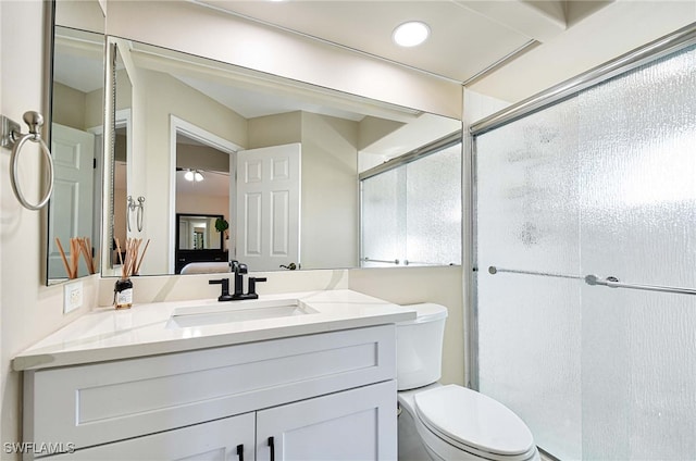 bathroom featuring a shower with shower door, vanity, and toilet