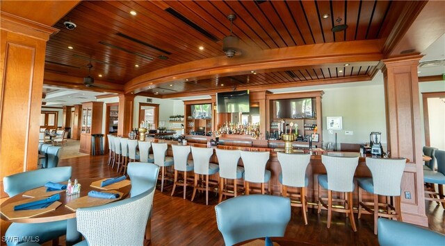 bar with beam ceiling, wood ceiling, dark hardwood / wood-style floors, and decorative columns