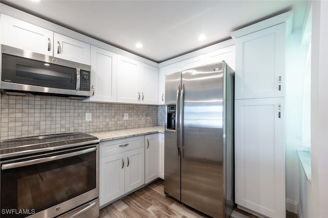 kitchen featuring tasteful backsplash, white cabinetry, light hardwood / wood-style flooring, and stainless steel appliances