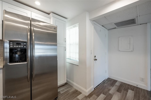 kitchen featuring a paneled ceiling, dark wood-type flooring, stainless steel fridge with ice dispenser, electric panel, and white cabinetry