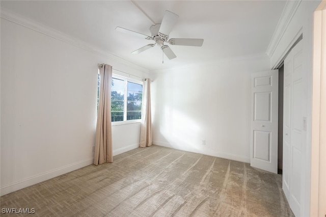 carpeted empty room with ceiling fan and crown molding