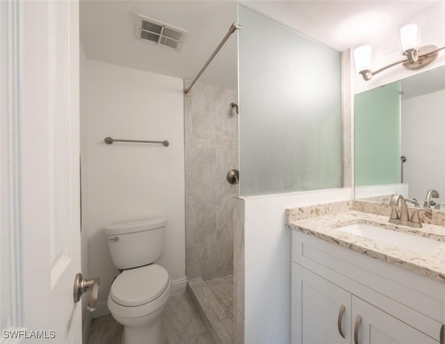 bathroom with toilet, vanity, and tiled shower