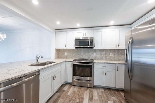 kitchen with white cabinetry, sink, stainless steel appliances, backsplash, and light hardwood / wood-style floors