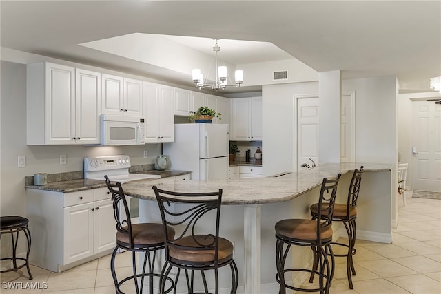 kitchen featuring a kitchen breakfast bar, kitchen peninsula, white cabinetry, and white appliances