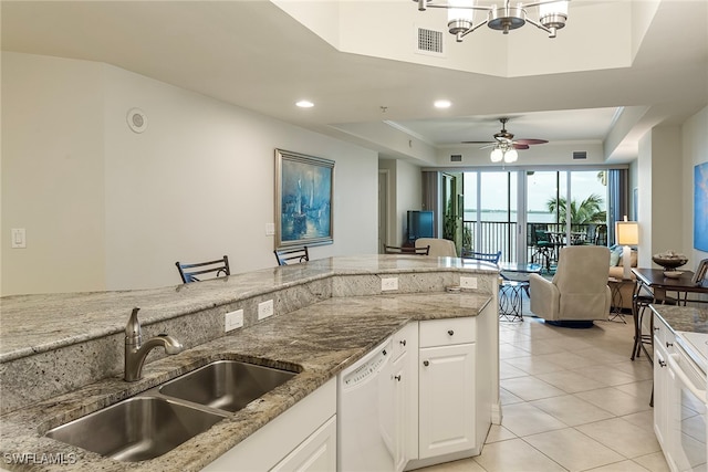 kitchen featuring a raised ceiling, white cabinetry, white dishwasher, ceiling fan with notable chandelier, and sink