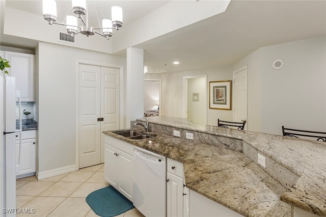 kitchen with white cabinets, hanging light fixtures, light stone countertops, sink, and white appliances