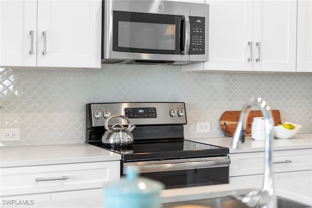 kitchen with stainless steel appliances, decorative backsplash, and white cabinets