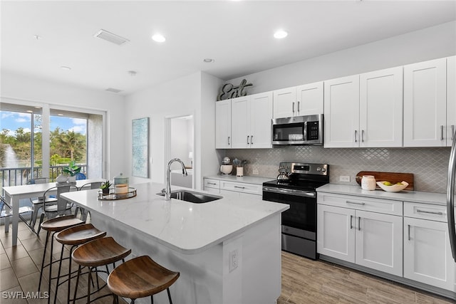 kitchen with a center island with sink, white cabinets, stainless steel appliances, and sink