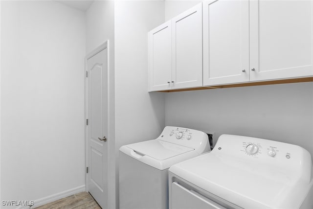 washroom with cabinets, washing machine and clothes dryer, and light hardwood / wood-style floors