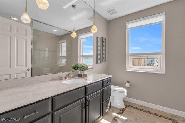 bathroom featuring tiled shower, vanity, and toilet