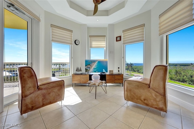 sitting room with a raised ceiling, ceiling fan, and light tile patterned floors