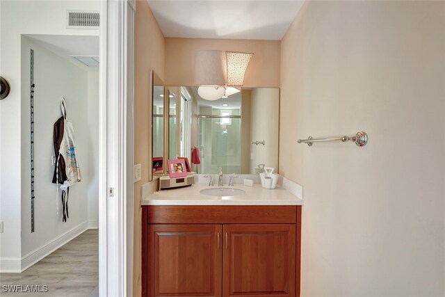 bathroom featuring hardwood / wood-style flooring, vanity, and a shower with shower door