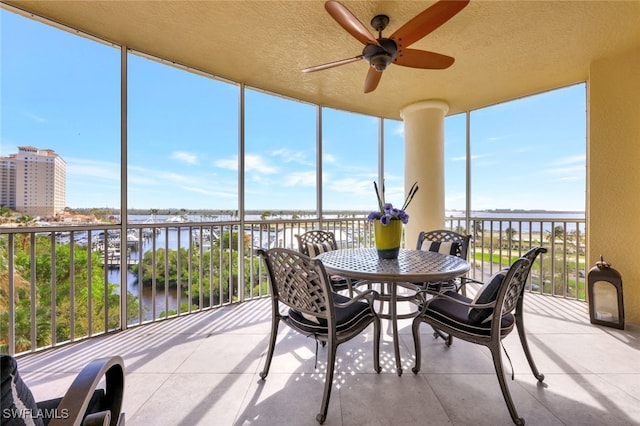 sunroom with a water view and ceiling fan