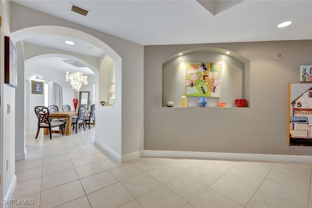 corridor featuring light tile patterned floors and an inviting chandelier