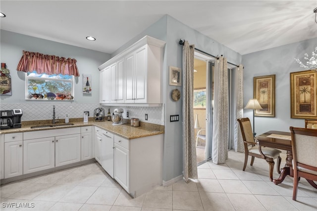 kitchen featuring backsplash, sink, white cabinetry, and a healthy amount of sunlight