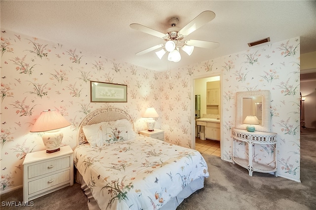 carpeted bedroom featuring a textured ceiling, connected bathroom, and ceiling fan