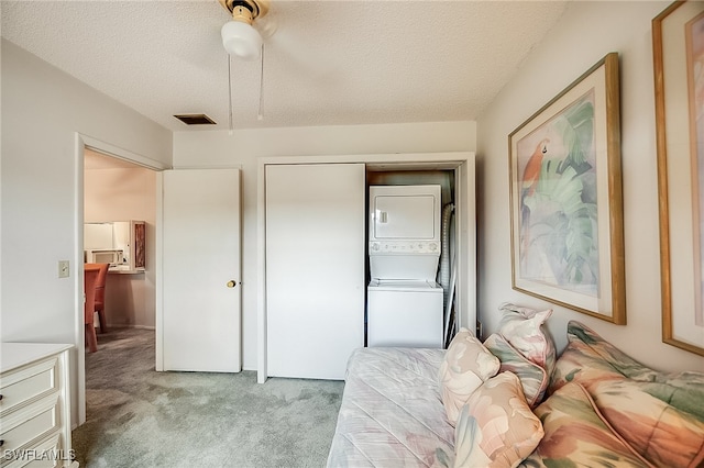 bedroom with stacked washer / dryer, ceiling fan, a textured ceiling, a closet, and light colored carpet